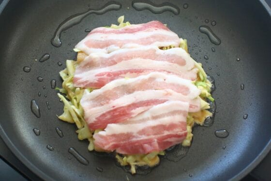 フライパンにお好み焼きの生地を広げて豚バラをのせる