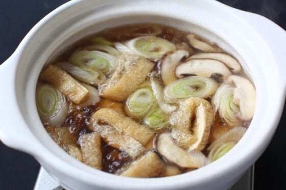 鶏肉・長ねぎ・しいたけ・油揚げをつゆで煮る