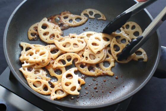 炒めたレンコンに調味料を絡める
