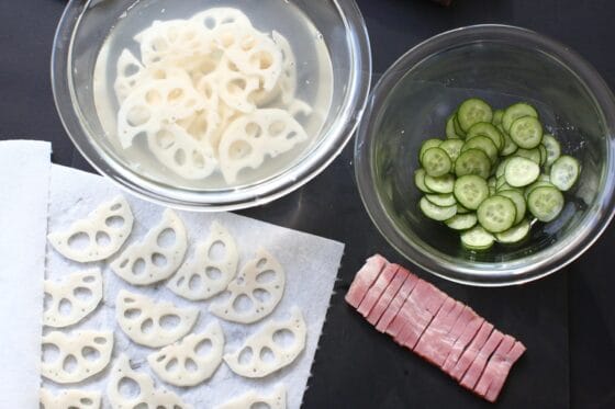 れんこんを切って酢水にさらし、きゅうりを切って塩をまぶし、ベーコンを切る