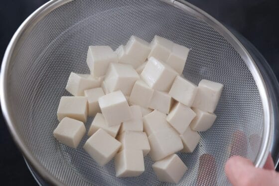 豆腐をザルにあげる
