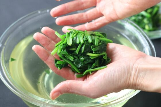 茹でたほうれん草を冷水に浸して水気を絞る