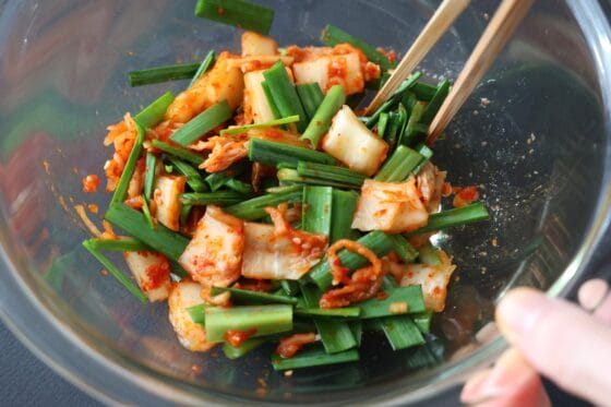 ニラとキムチを調味料と一緒にボウルで和える