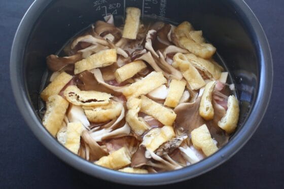 米の上に里芋や鶏肉などの具材を順番に広げる