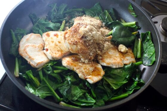 炒めたほうれん草に鶏肉と調味料を加える