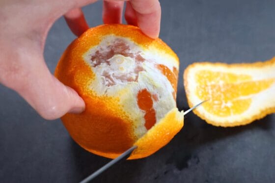 デコポンの皮と白い部分を包丁でそぎ落とす様子