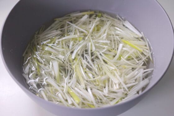 細切り長ねぎを水にさらして辛味を抜くネギサラダの下処理