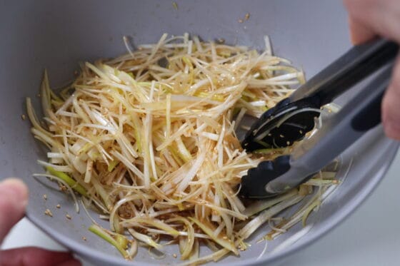 長ネギと白ごまを調味料で和えるネギサラダの仕上げ