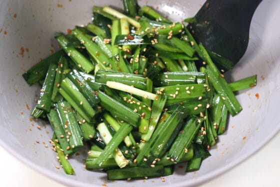 白いりごまを加えてニラを和える仕上げ