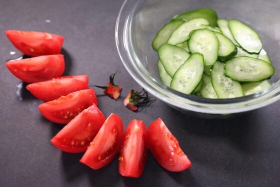 トマトをくし切りにしきゅうりを薄切りにして塩をまぶす下ごしらえ