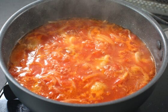 トマト缶と水を加えて煮る
