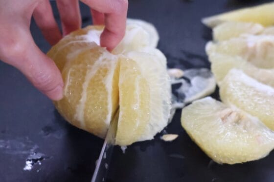 文旦の表面の白いわたを削いだあとに房の境目に沿って包丁を入れる