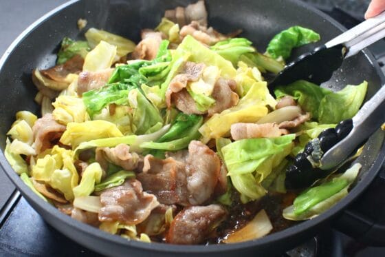 春キャベツと豚バラに調味料を加えて全体に絡めながら炒める
