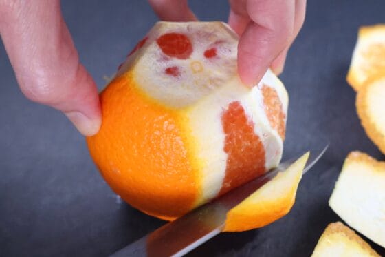 オレンジの外皮を包丁で削ぐ