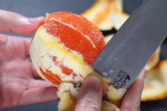 オレンジの薄皮と白い綿を包丁でむく