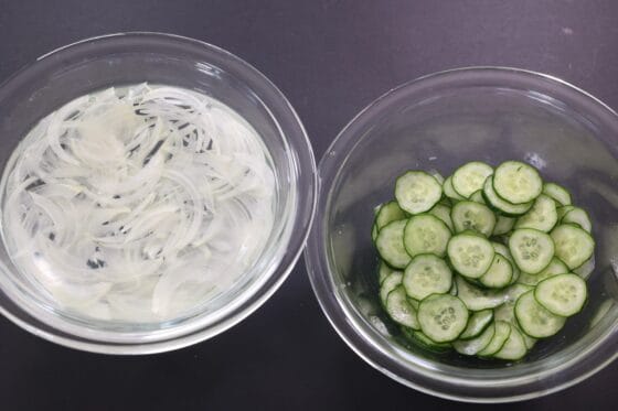 玉ねぎときゅうりを薄切りにして下処理する