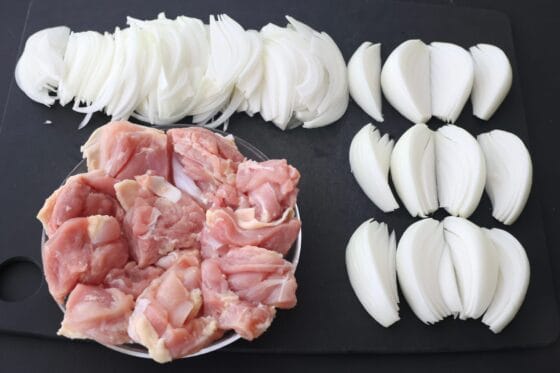 新玉ねぎを薄切りとくし切りにし鶏肉を切る下ごしらえ