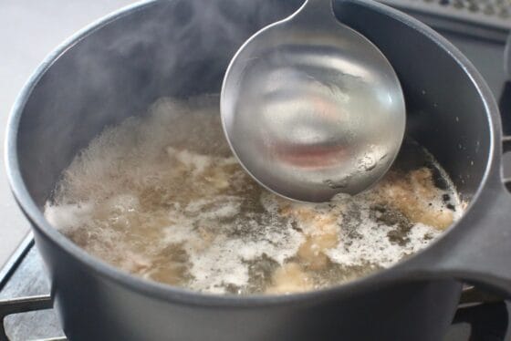 鶏肉を煮ながらアクを取り除く