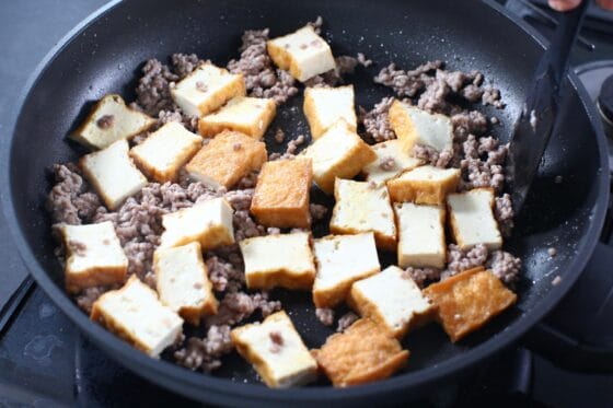 厚揚げと豚ひき肉を炒め合わせる