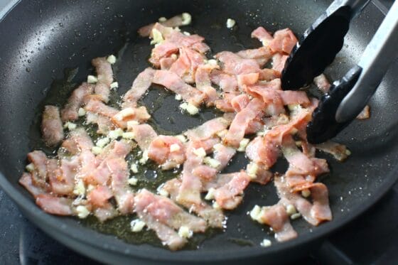炒めたベーコンににんにくを加える