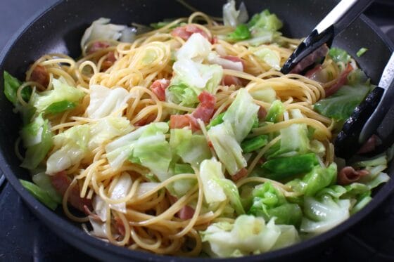 醤油を加えて春キャベツのパスタを仕上げる