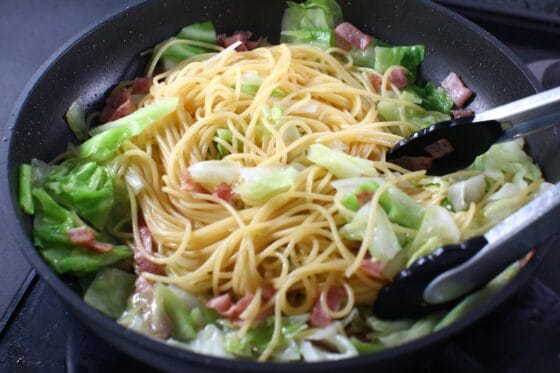 春キャベツとパスタをフライパンで混ぜる