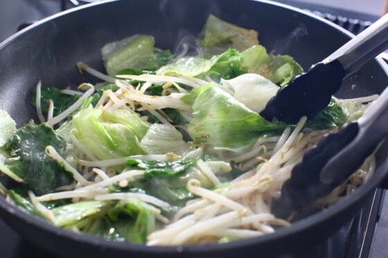 レタスともやしに調味料を加えて炒める