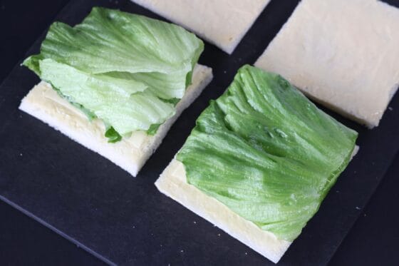 パンにバターとマヨネーズを塗り折りたたんだレタスをのせる