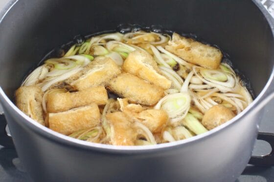 つゆで長ネギと油揚げを煮る