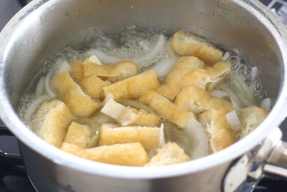 煮た新玉ねぎに油揚げを加える
