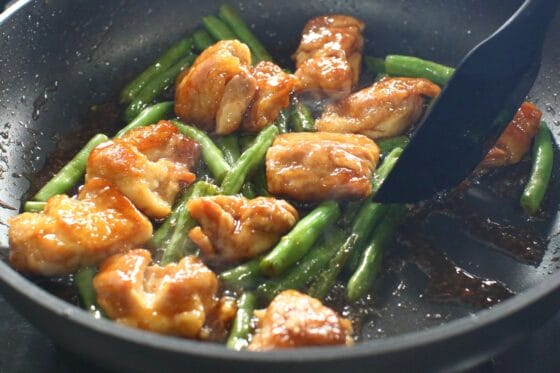 甘辛だれを加えて鶏もも肉といんげんに絡める