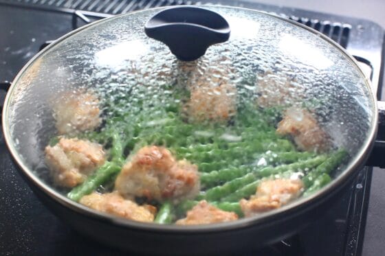 鶏もも肉といんげんをふたをして蒸し焼きにする