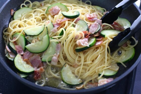 ズッキーニとパスタにソースをからめる