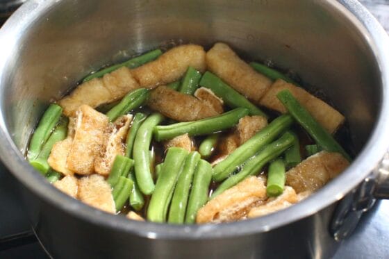煮立った煮汁にいんげんと油揚げを加える