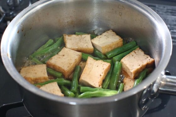 厚揚げを煮た鍋にいんげんを加え、煮汁になじませる