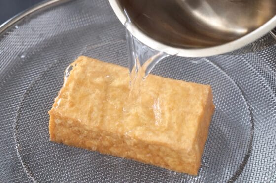 厚揚げの両面に熱湯をかけて油抜きする
