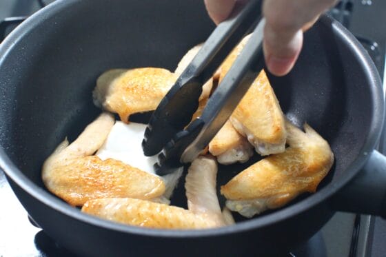 手羽先を焼いて出た余分な脂をキッチンペーパーで拭き取る