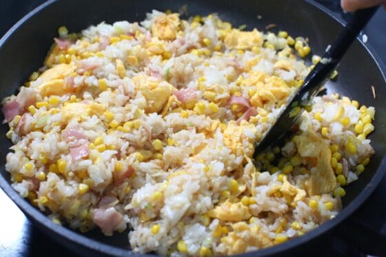 とうもろこしチャーハンに半熟卵と調味料を加えて炒め合わせる