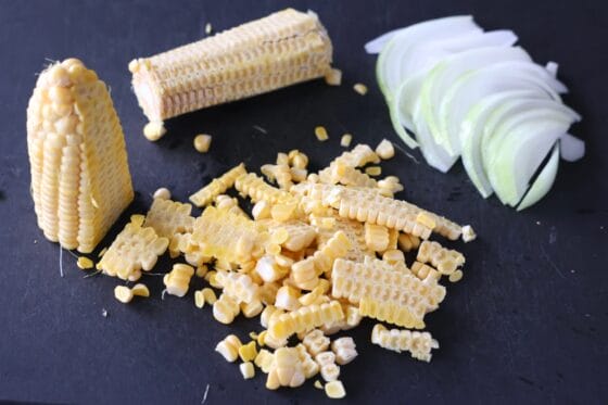 とうもろこしの実をそぎ落とし、玉ねぎを薄切りにする
