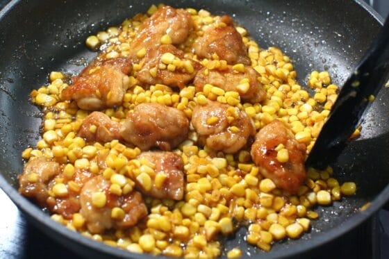 鶏肉ととうもろこしにたれとバターを絡め、照りよく仕上げる