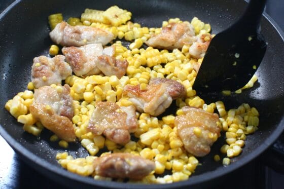 焼いた鶏肉にとうもろこしを加え、油がまわるまで炒め合わせる