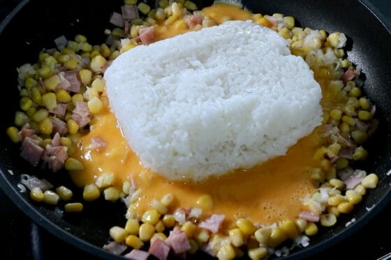 炒めた具材を端に寄せ、溶き卵と温かいご飯をフライパンに加える