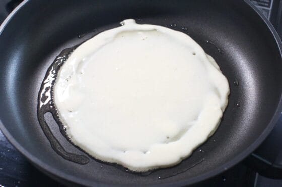 キャベツ焼きの生地を中火のフライパンに流し、円形に薄く広げる
