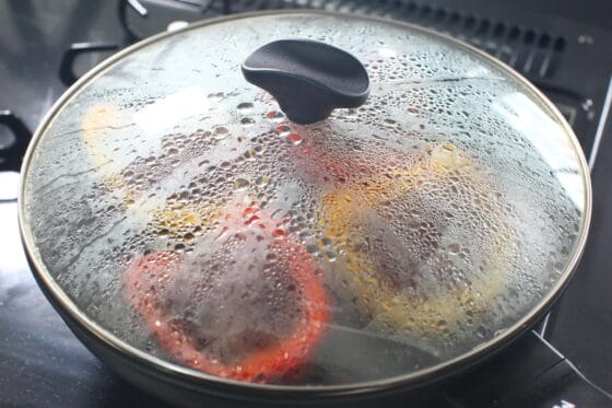 パプリカの肉詰めに水を加え、フタをして弱めの中火で蒸し焼きにする