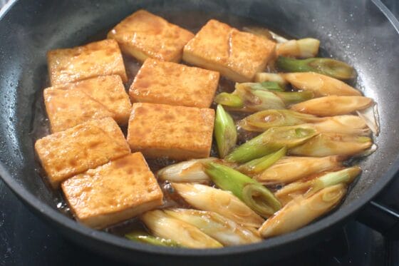 豆腐と長ネギを甘辛い煮汁で煮て、煮汁が大さじ3程度残るまで煮る