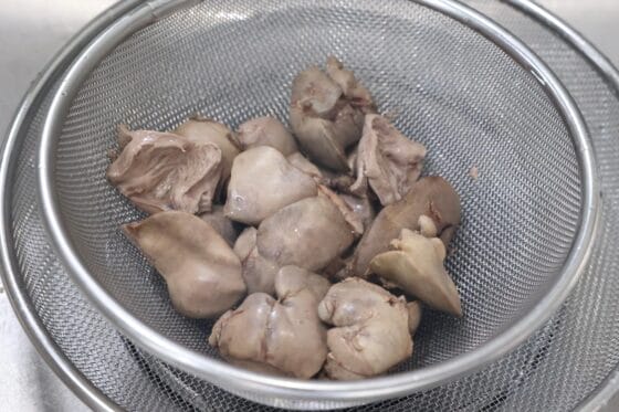 下茹でした鶏レバーとハツを網じゃくしで取り出し、ざるに上げて水気を切る