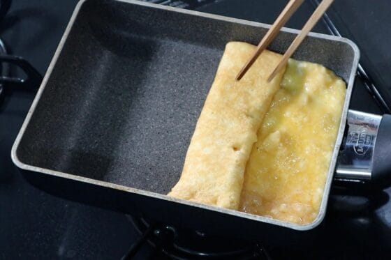 表面が半熟になったはんぺん入り卵焼きを卵焼き器の奥から手前に巻く