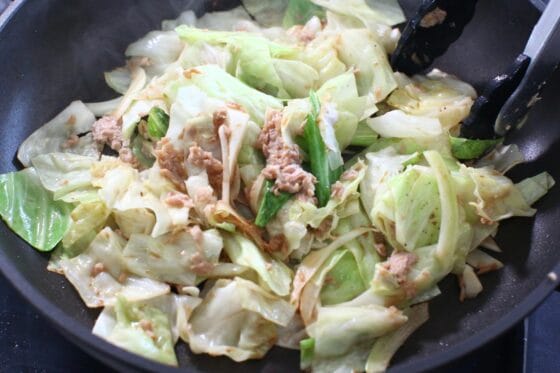 キャベツとツナにこしょうと醤油を加え、全体を手早く炒め合わせる
