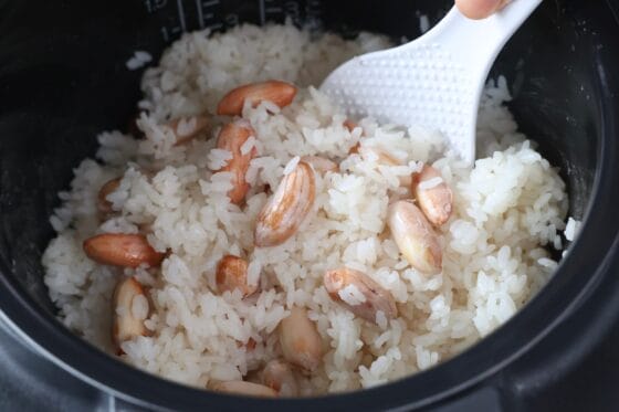 炊き上がった生落花生の炊き込みご飯を底からさっくり混ぜる