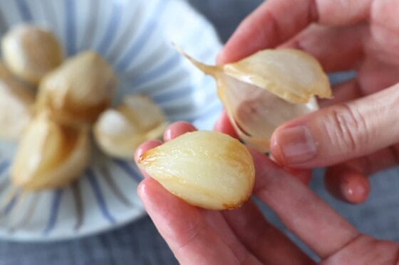 素揚げしたにんにくの薄皮をむき、柔らかく仕上がった中身を取り出す